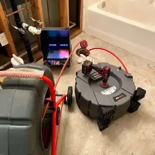 Drain cleaning equipment, including a camera inspection system and a power auger, set up in a bathroom for plumbing service.